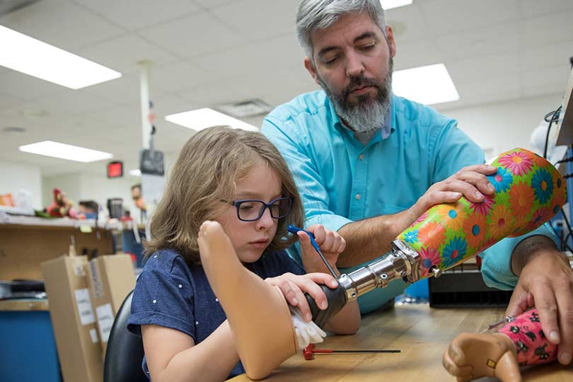 A prosthetist making a new device with a patient watching