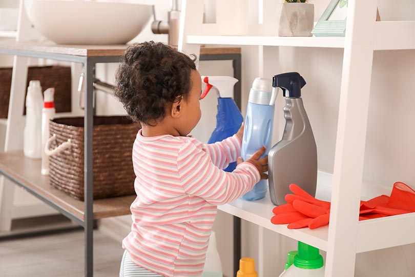 Child touching household cleaning bottles