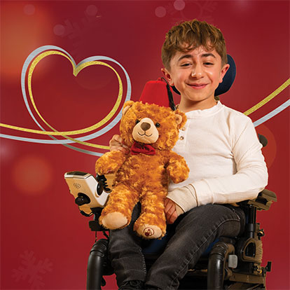 patient in wheelchair, smiling and holding toy bear