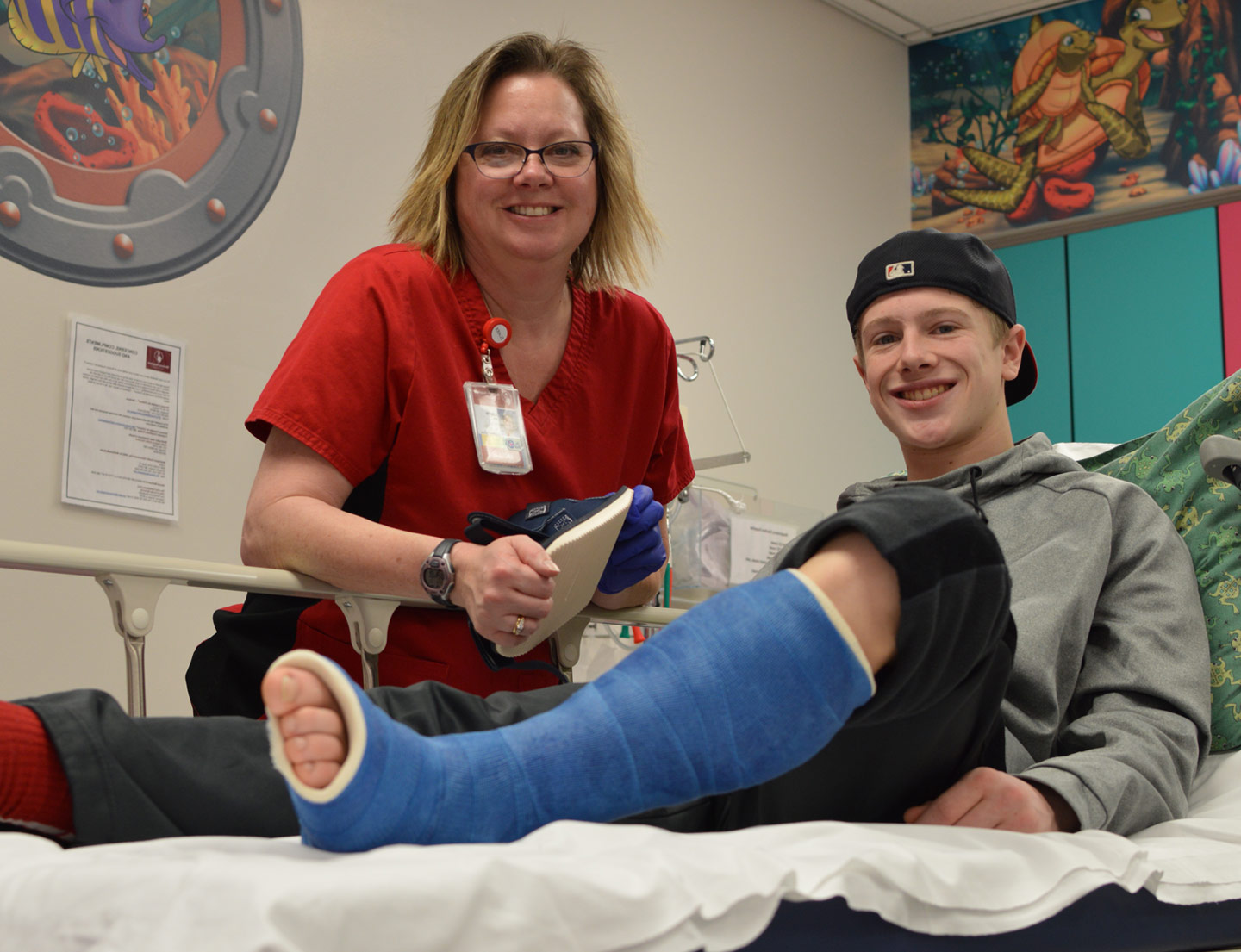 paciente con una fractura que tiene un yeso en la pierna junto con personal de enfermería