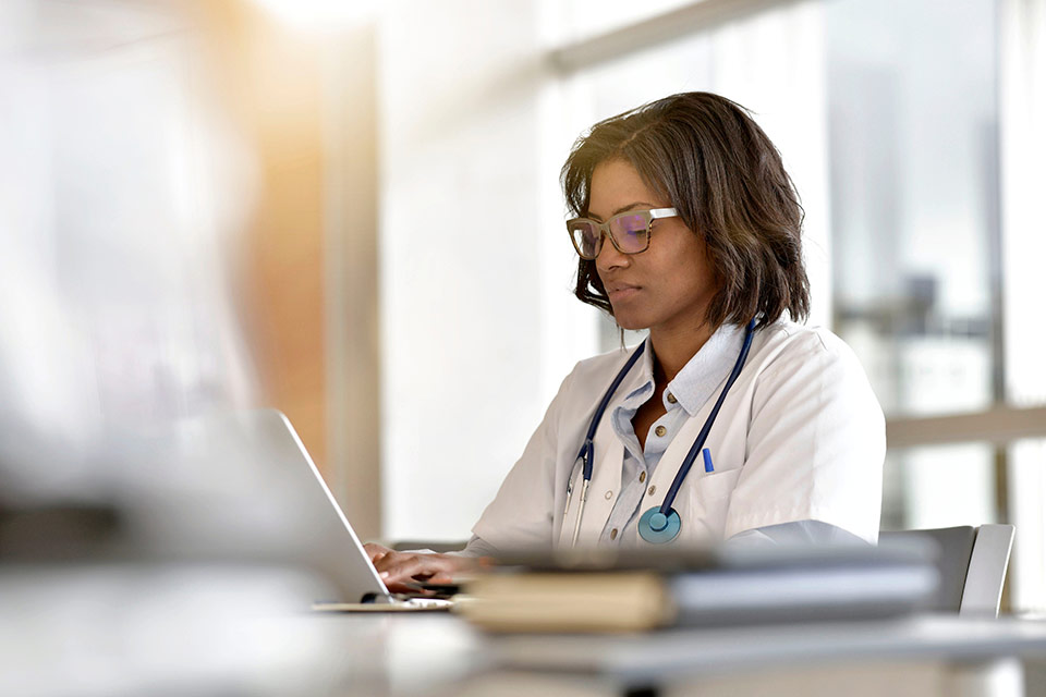 female provider sits at desk typing on a laptop