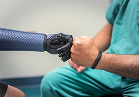 un bras et une main orthétiques tapent dans la main d’un médecin