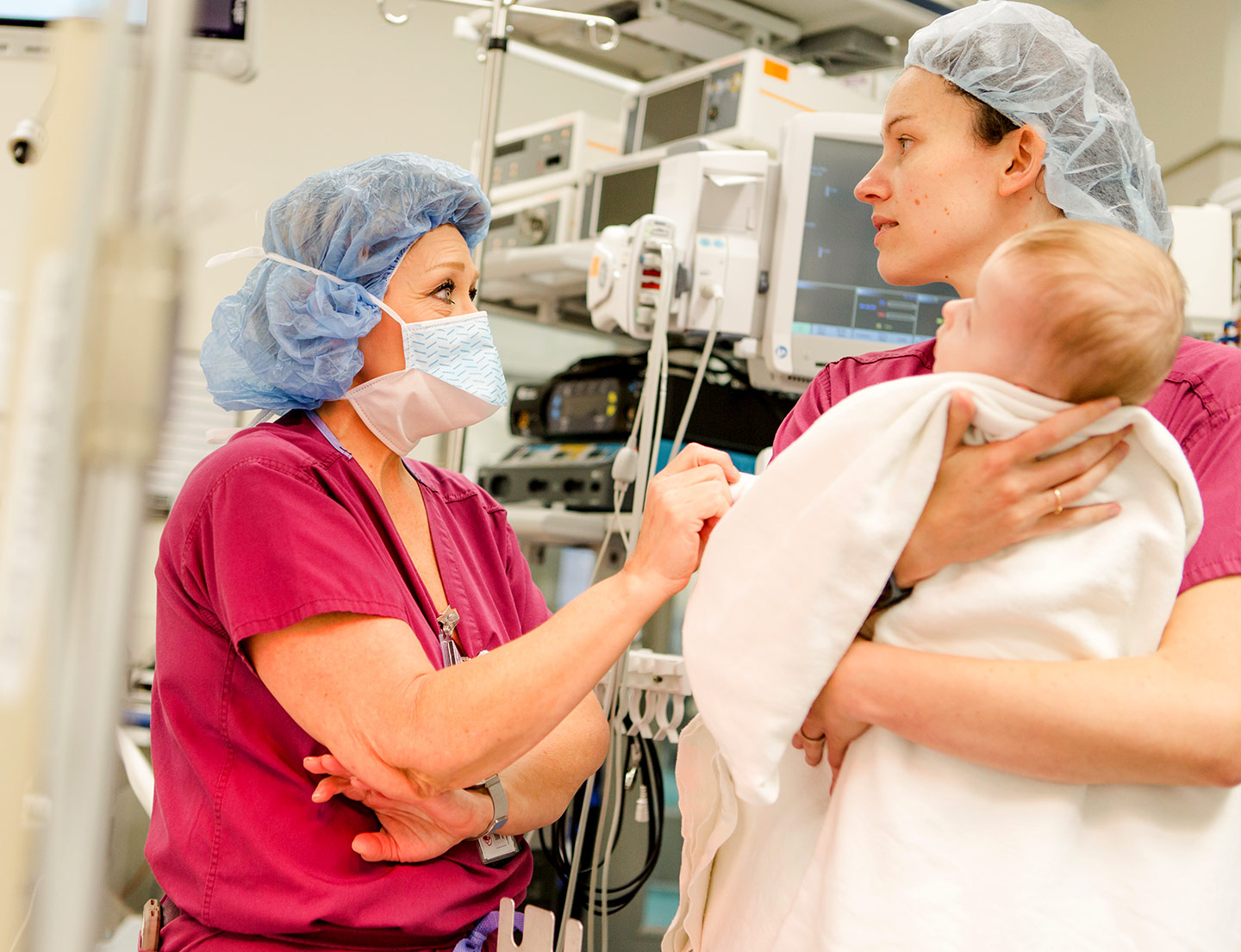 two nurses, one holding baby patient