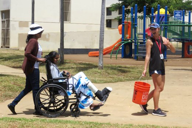 Paciente en silla de ruedas y miembros del personal en el patio de juegos.
