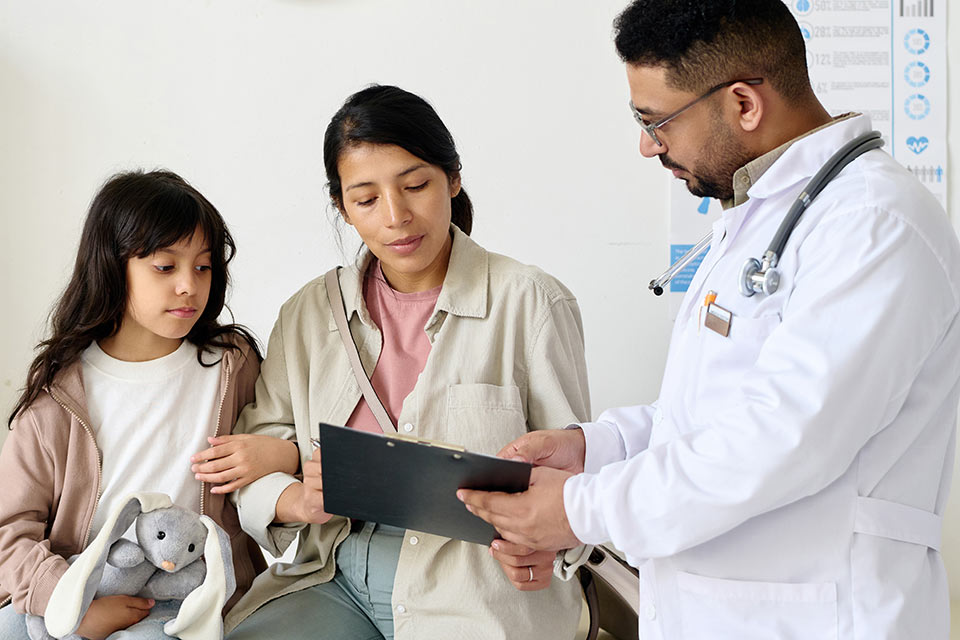Doctor showing medical chart to mom and daughter
