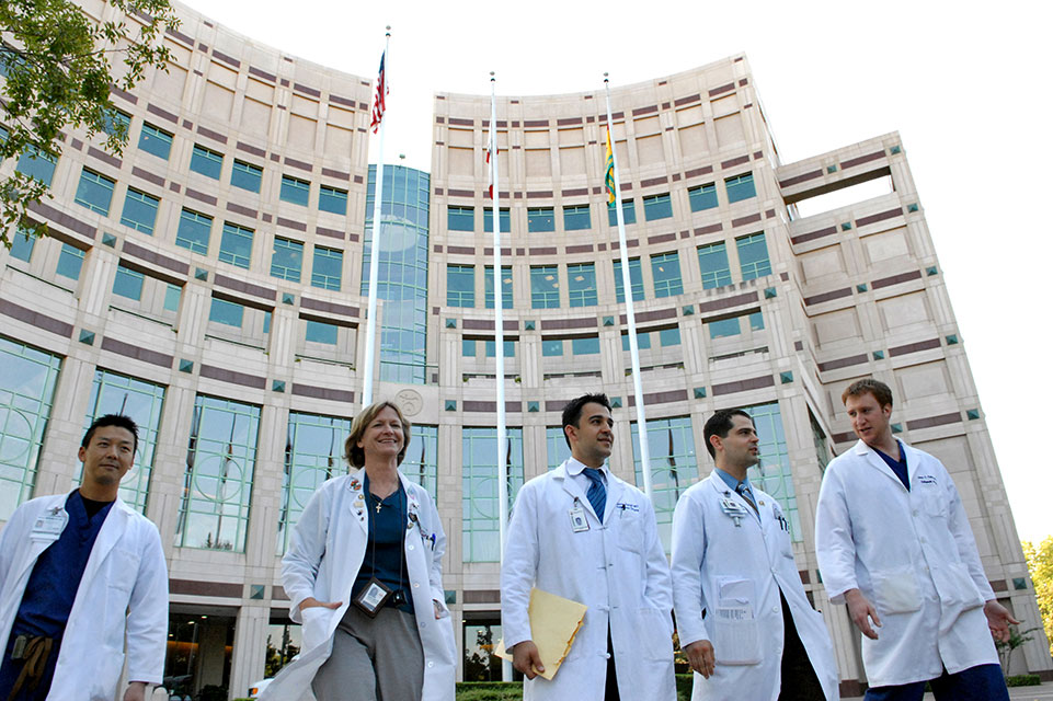five physicians in front of hospital building