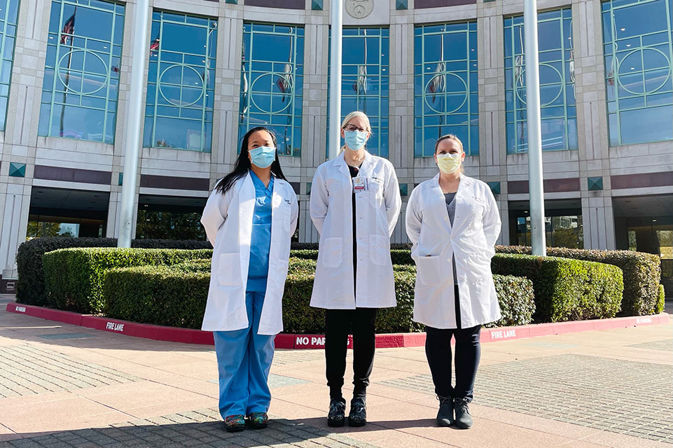 three physicians in front of hospital building