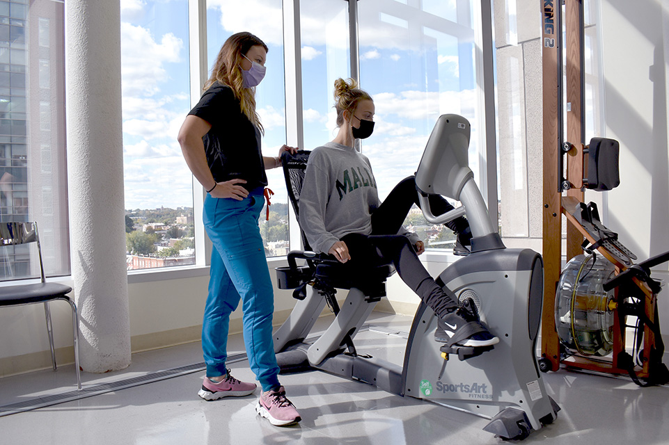 Therapist with a patient who is on exercise bike
