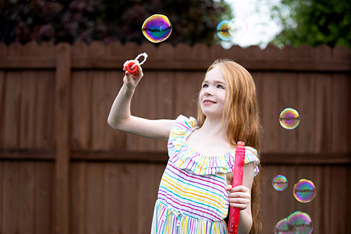 niña afuera jugando con burbujas
