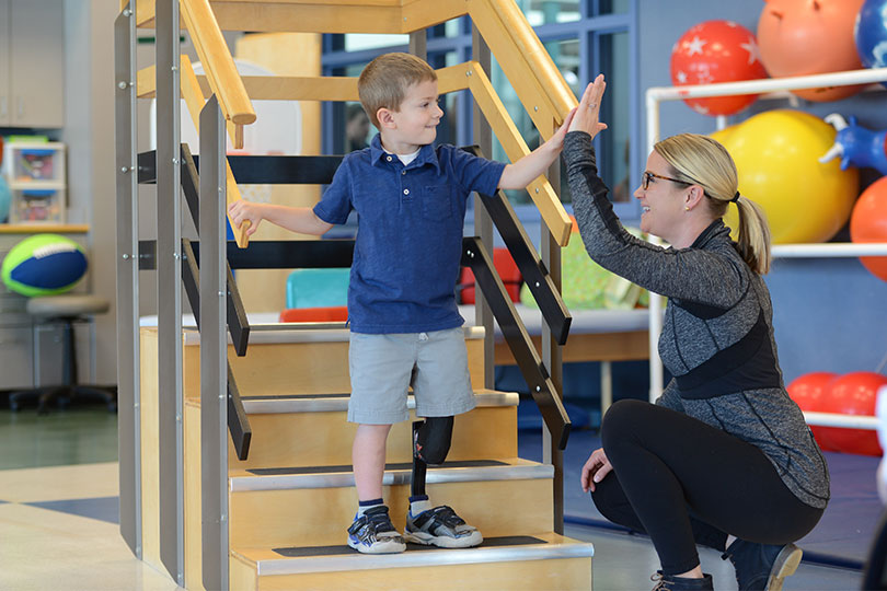 patient and physical therapist share high five during physical therapy session