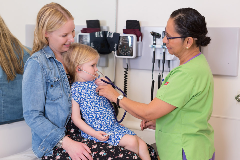 parent holding patient while staff member lets patient use stethoscope