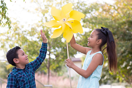 deux enfants jouant avec un grand moulin à vent jaune