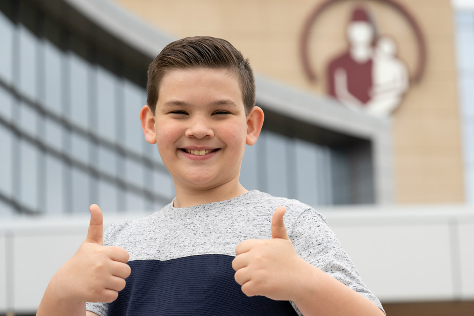 male patient in front of hospital giving two thumbs up