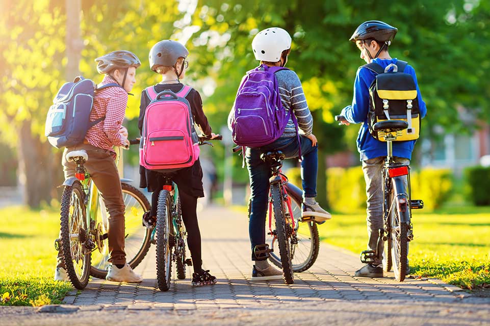children wearing backpacks on bicycles