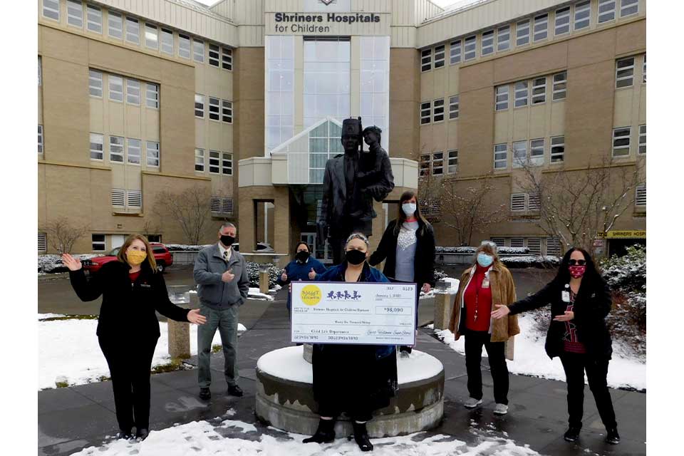 miembros de personal con cheque gigante frente al hospital spokane
