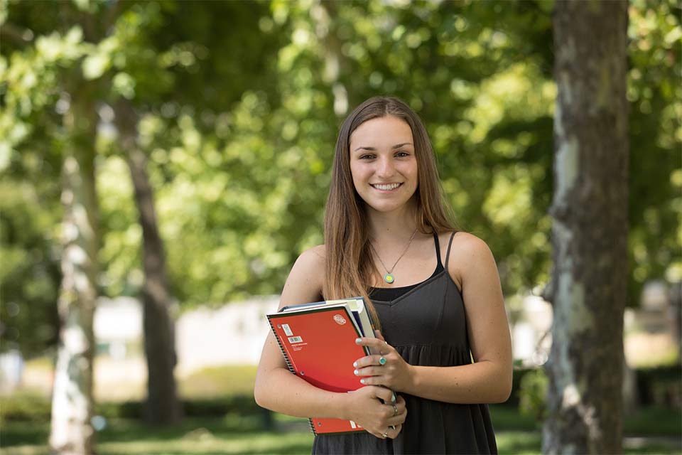 Female scoliosis patient outside, holding books