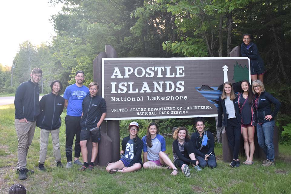 campers and counselors in front of camp sign