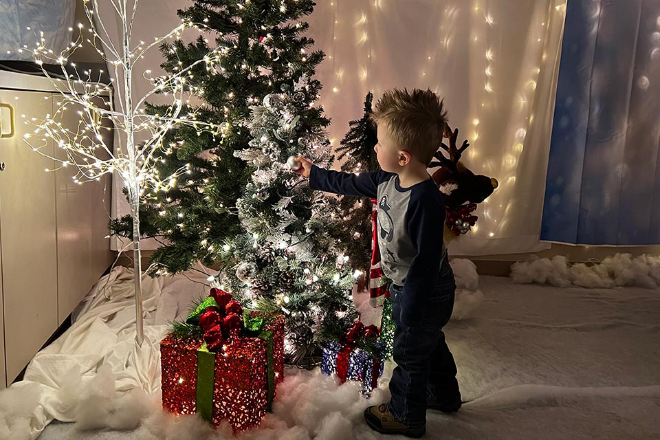 Little boy hanging Christmas ornament on tree