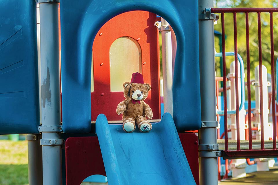 Fezzy the Bear on a playground sliding board