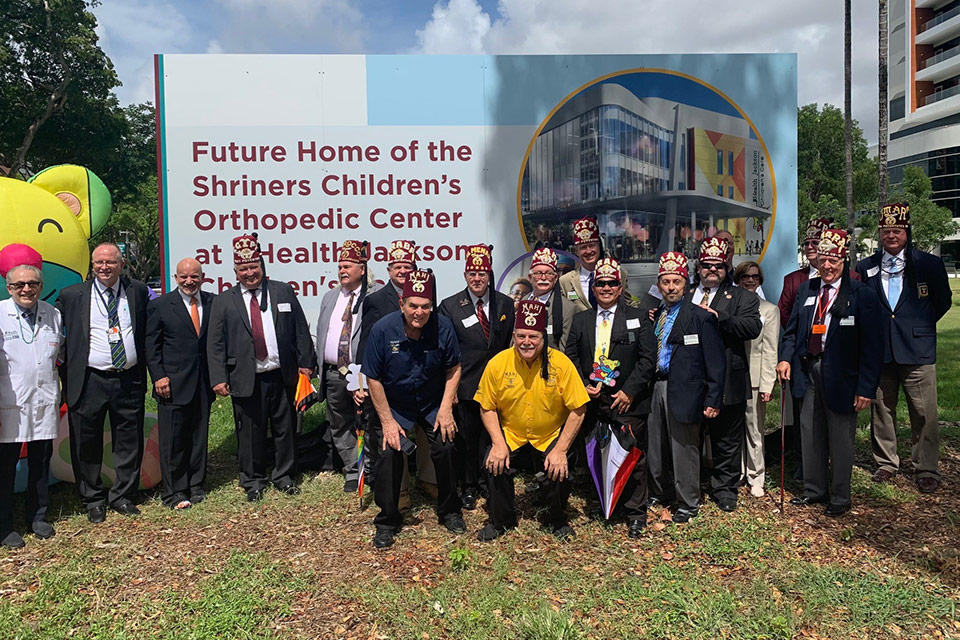 Shriners, staff and administrators by sign that says Future Home of the Shriners Children's Orthopedic Center at UHealth Jackson Children's Care