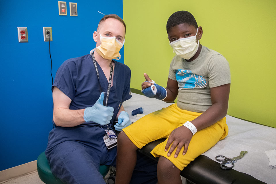 Doctor with patient in an arm cast giving thumbs up