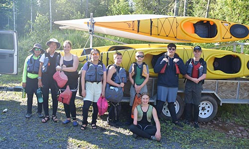 eight campers in front of kayak trailer
