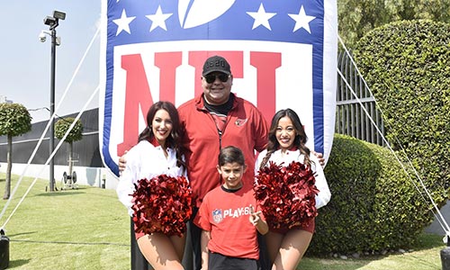 patient with cheerleaders and Cardinals coach in front of NFL banner