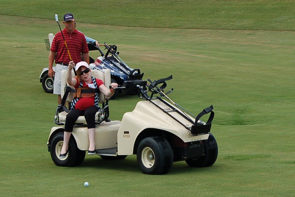 Patiente jouant au golf assise sur une voiturette de golf