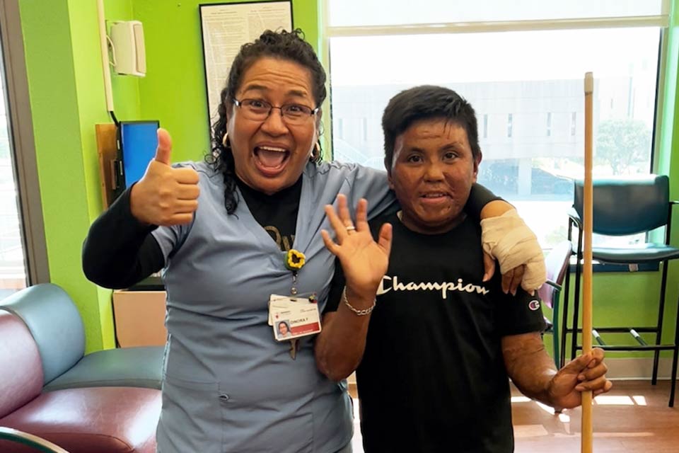 Dinora giving a thumbs up with waving male patient