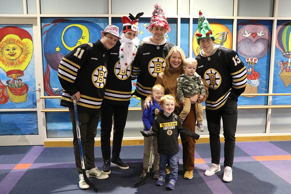 Three Bruins players with parent and patients