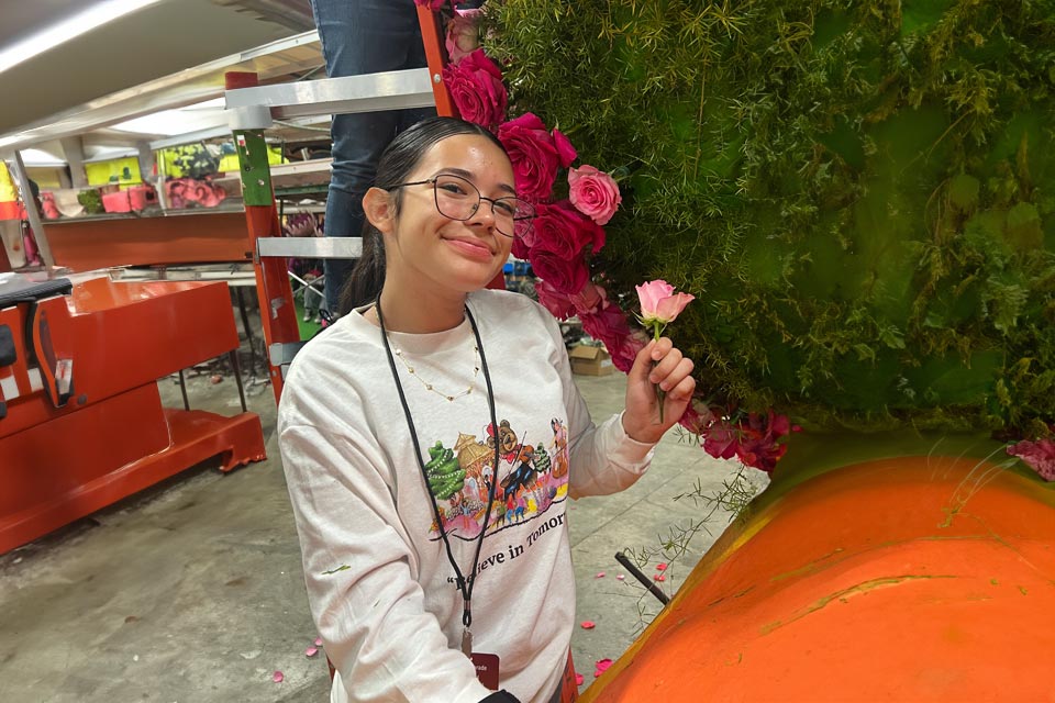 Danna holding flower in front of float