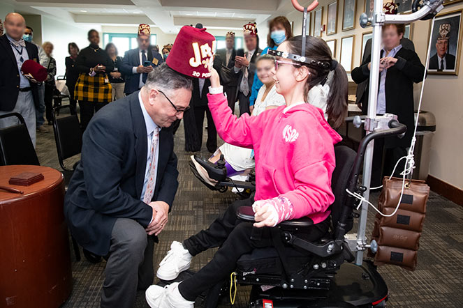 patient in wheelchair placing fez on a Shriner
