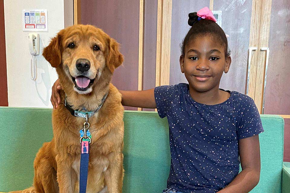 therapy dog sitting with female patient in blue shirt