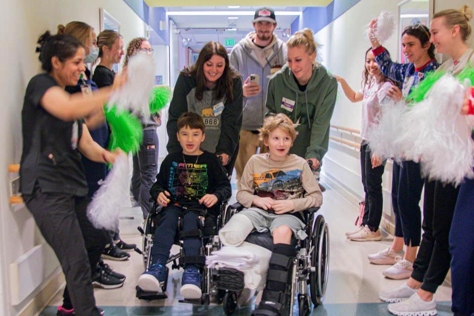 pacientes en sillas de ruedas y personal celebrando en el pasillo con pompones