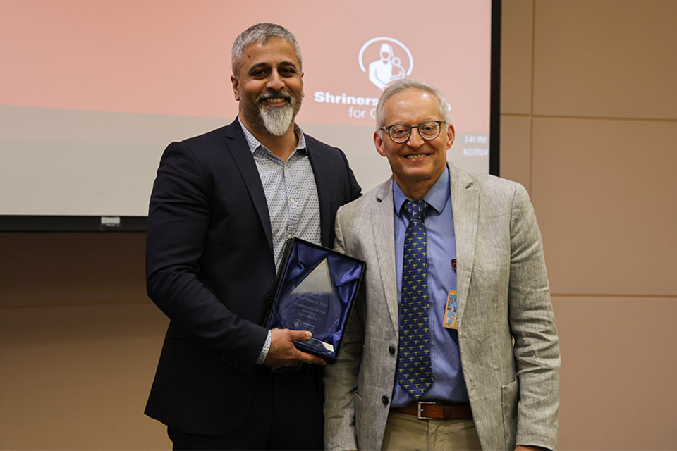 Firoz Miyanji, M.D., FRCSC, recibe un premio de manos de Rolando Roberto, MD, jefe de personal del Hospital Shriners para Niños Northern California