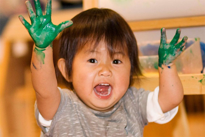 A very young Natalie with green paint on her hands