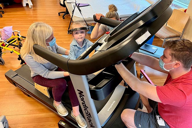 Kennedy in halo traction on treadmill, two therapists