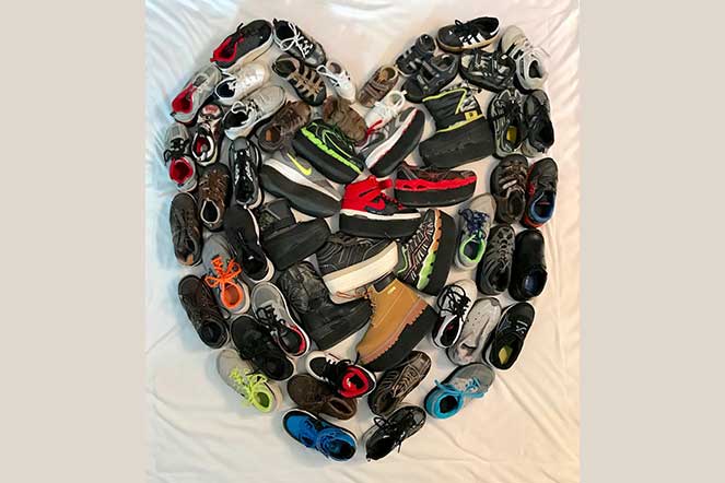 Many pairs of shoes laying in a heart shape