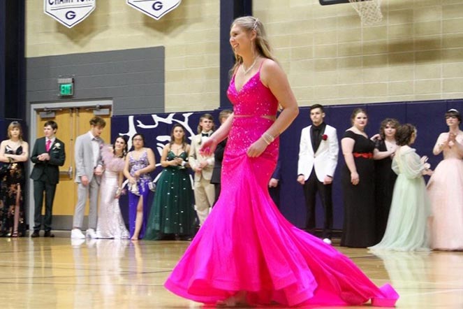 Malorie caminando con un vestido rosa fuerte durante el baile de graduación