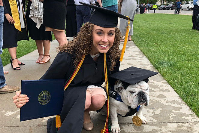 Elliana in cap and gown next to a dog with cap on
