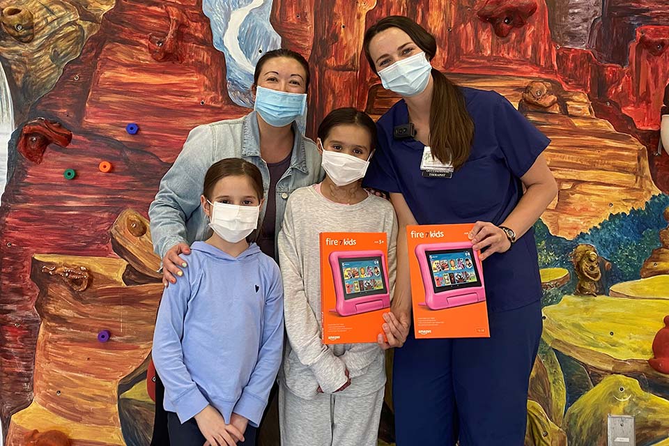 Cadence and sister Madsion standing with hospital staff memeber holding tablets