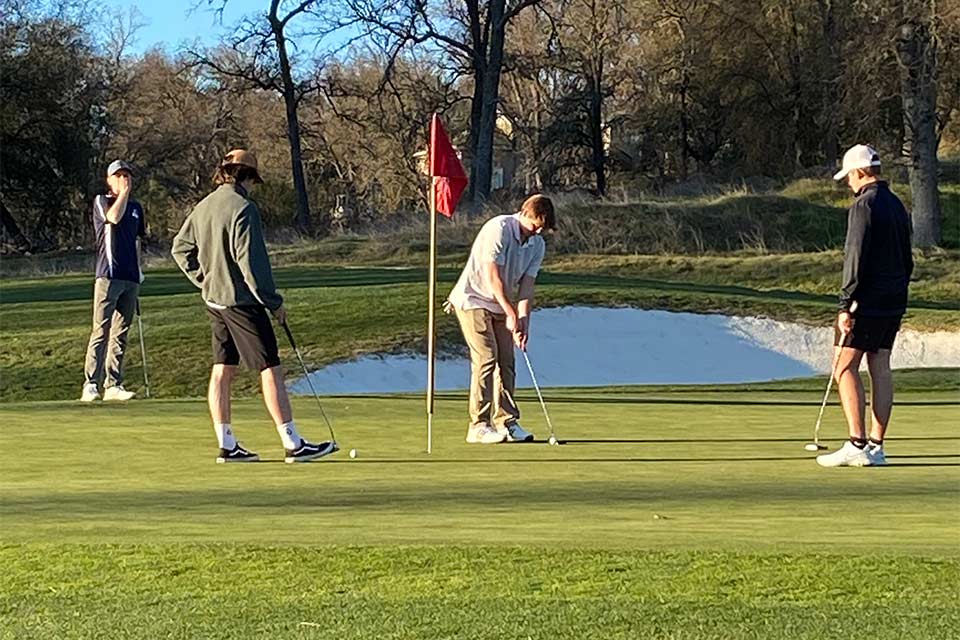 Sammy putting with three onlookers