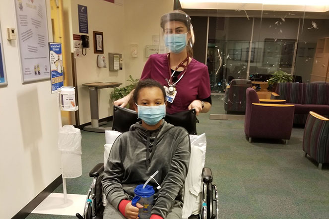 Kira in wheelchair with staff member