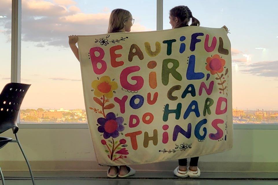 Macie and Lou Lou holding banner that says Beautiful Girl, You can Do Hard Things