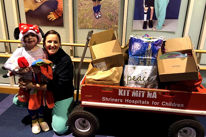 Emily and mom with wagon full of donations, wagon says "Shriners Hospitals for Children"