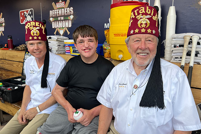 Gavin with two Shriners in baseball dugout