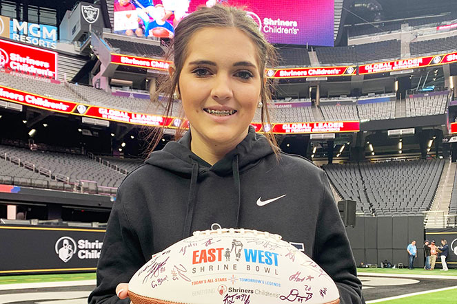 Madison holding signed East/West Shrine Bowl football