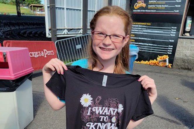 Faith sosteniendo una camiseta que dice "I Want To Know What Love Is"