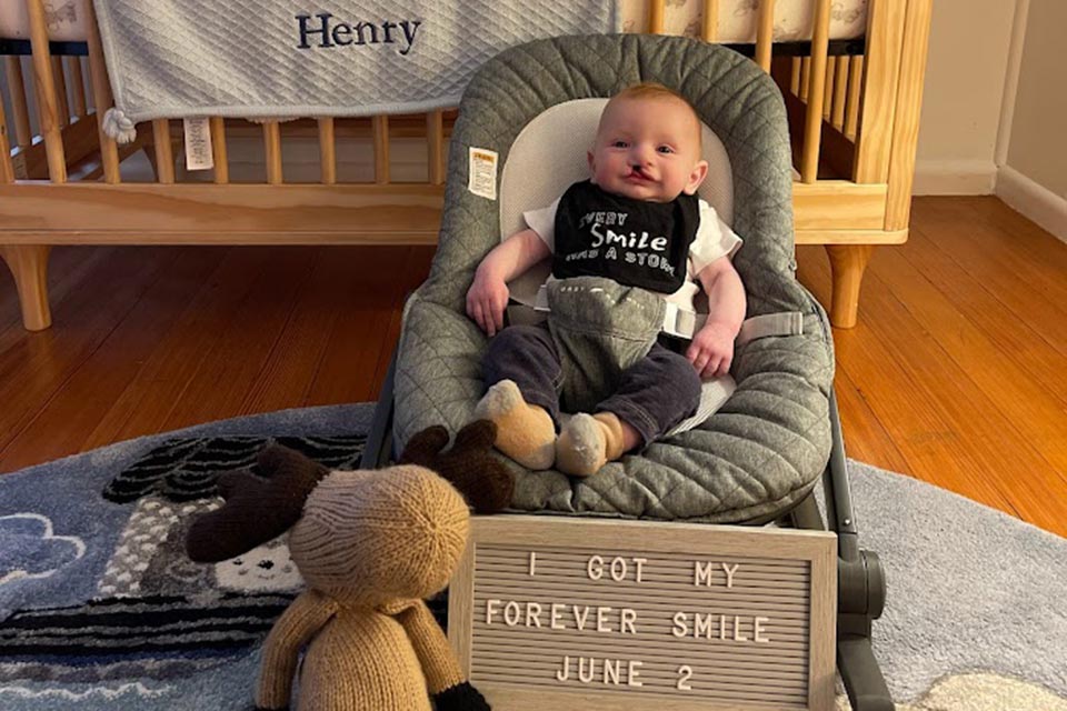 Henry cuando era un bebé, cartel frente a él que dice "Obtuve mi sonrisa para siempre el 2 de junio"