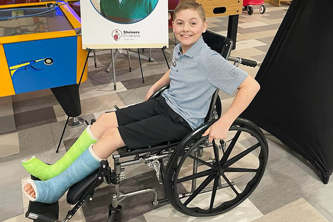Un patient souriant dans des plâtres de jambe et assis en fauteuil roulant